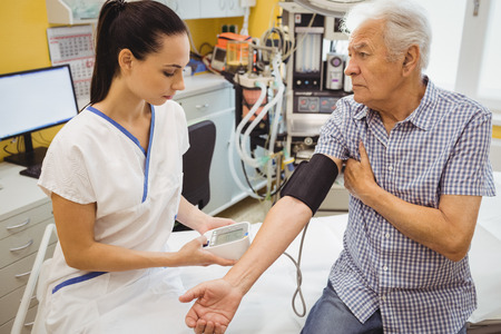 Female doctor checking blood pressure of patient at the hospital