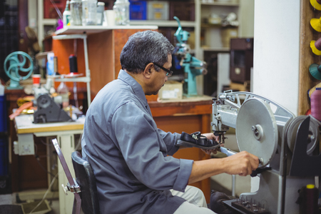 Shoemaker using sewing machine in workshopの写真素材