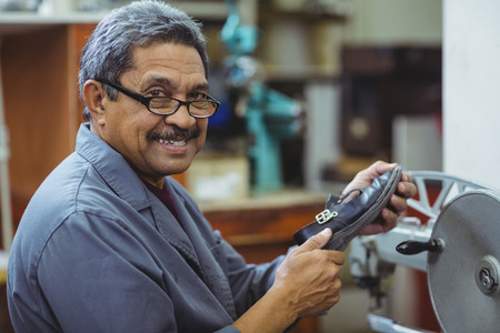 Portrait of shoemaker using sewing machine in workshopの写真素材
