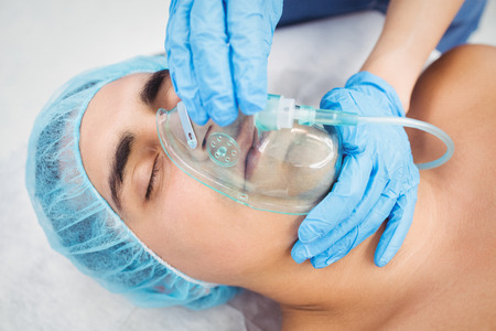 Nurse putting an oxygen mask on patient in operation room at the hospital