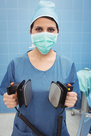 Portrait of female surgeon holding defibrillator at the hospitalの写真素材