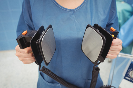 Mid section of female surgeon holding defibrillator at the hospitalの写真素材