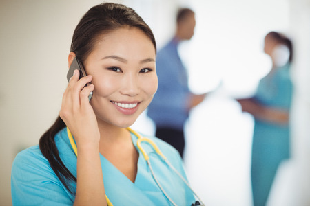Portrait of nurse talking on mobile phone in hospitalの写真素材