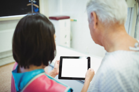 Female doctor discussing with patient over digital tablet at the hospitalの写真素材