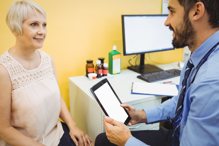 Doctor discussing with patient over digital tablet at the hospitalの写真素材
