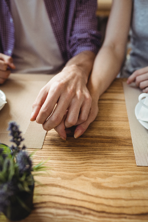 Mid-section of couple holding hands in bakery shopの写真素材