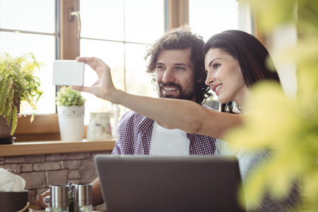 Couple taking selfie from mobile phone in bakery shopの写真素材