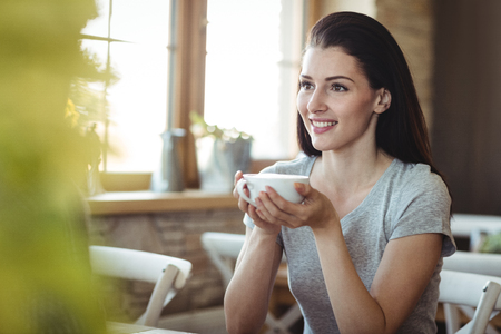 Woman holding a cup of coffee in bakery shopの写真素材