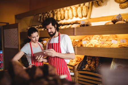 Couple using digital tablet in bakery shop