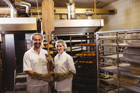 Portrait of female and male baker standing together in bakery shopの写真素材