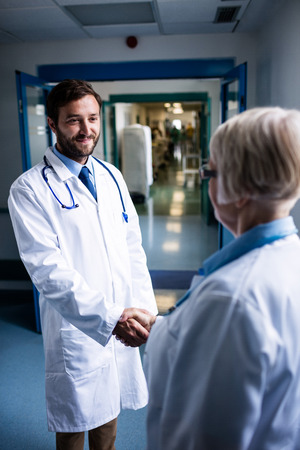 Doctors shaking hands in hospital corridorの写真素材