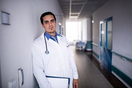 Portrait of sad doctor leaning against the wall in hospitalの写真素材