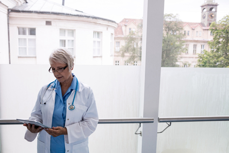 Doctor using digital tablet in hospital corridorの写真素材