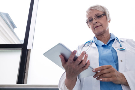 Doctor using digital tablet in hospital corridorの写真素材