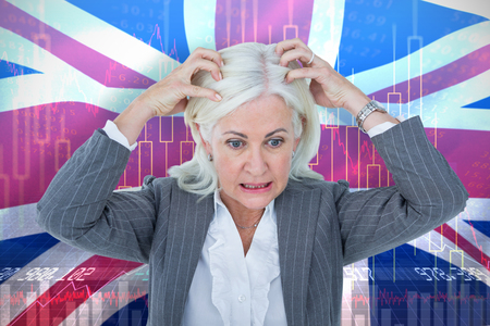 Stressed businesswoman with hands on head against digitally generated great britain national flagの写真素材