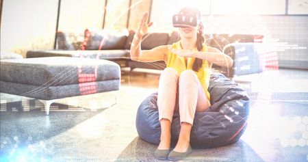 Composite image of face against  woman  wearing virtual reality simulator  Woman  wearing virtual reality simulator while gesturing at homeの写真素材