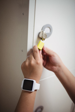 Female student locking her locker in collegeの写真素材