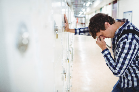 Sad student leaning on locker in collegeの写真素材