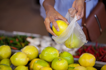 Mid section of woman buying sweet lime in supermarketの写真素材