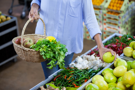 Mid section of woman buying sweet lime in organic section of supermarketの写真素材