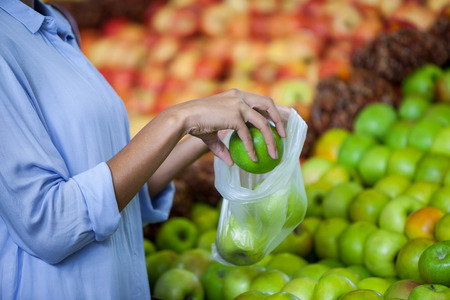 Mid section of woman buying an apple in supermarketの写真素材