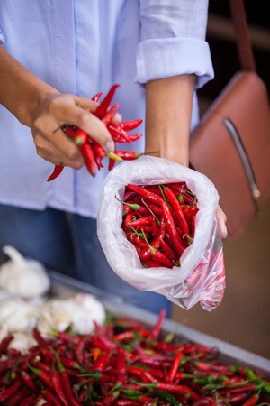 Mid section of woman buying red chilies in supermarketの写真素材