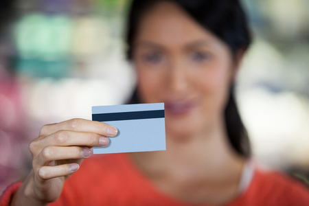 Close-up of woman holding credit card in supermarketの写真素材