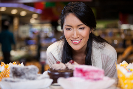Happy woman selecting desserts from display in supermarketの写真素材