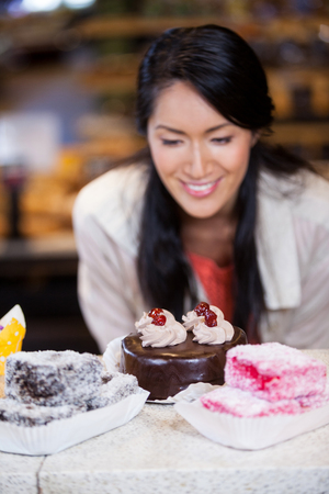 Happy woman selecting desserts from display in supermarketの写真素材