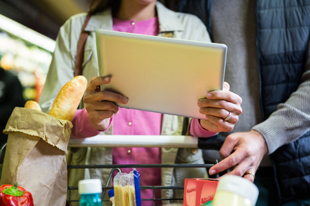 Couple using digital tablet while shopping in supermarketの写真素材