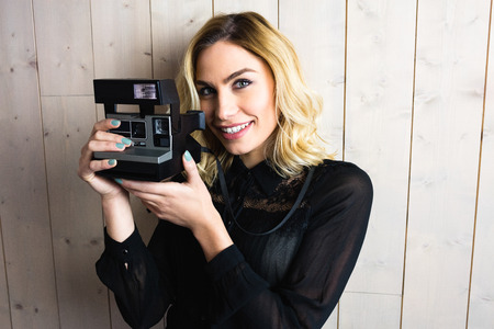 Portrait of woman holding a camera against texture background