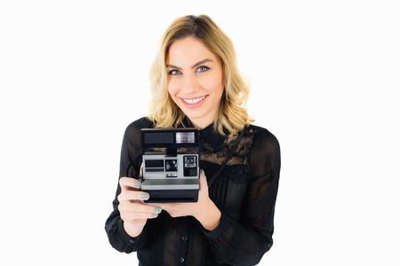 Portrait of smiling woman holding a camera against white backgroundの写真素材