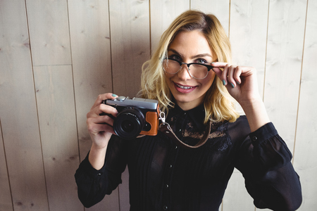 Portrait of woman posing with camera and spectacle against texture backgroundの写真素材