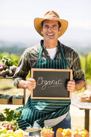 Portrait of a smiling farmer holding an organic signの写真素材