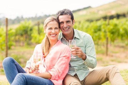 Portrait of happy couple holding glasses of wine in vineyardの写真素材