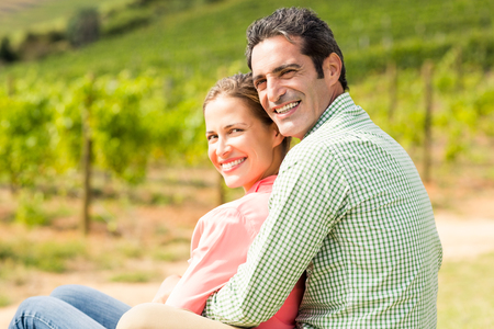 Portrait of happy couple sitting in vineyard on a sunny dayの写真素材