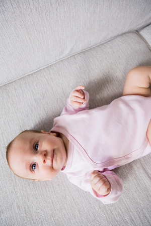 Baby lying on sofa in living room at homeの写真素材