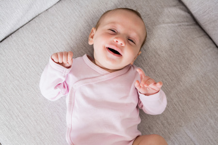 Smiling baby lying on sofa in living room at home