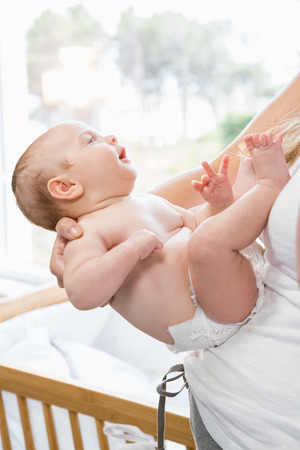 Mid-section of mother holding her baby boy at homeの写真素材