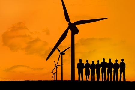digital composite of silhouette of group of people with windmills on orange sky background