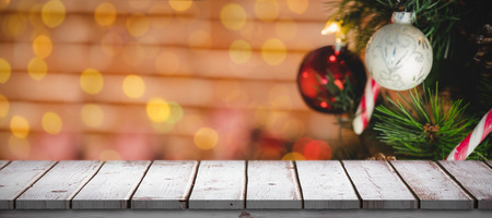 Wooden desk against bauble decorations on christmas treeの写真素材