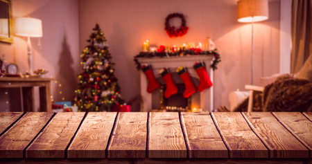 Wooden table against christmas tree with presents near the fireplaceの写真素材
