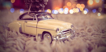 Toy car carrying christmas pine cone on fur carpet