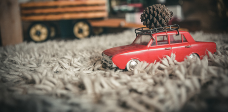 Toy car carrying christmas pine cone on fur carpetの写真素材