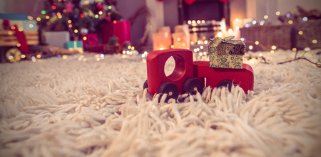 Toy car carrying christmas gift box on fur carpetの写真素材