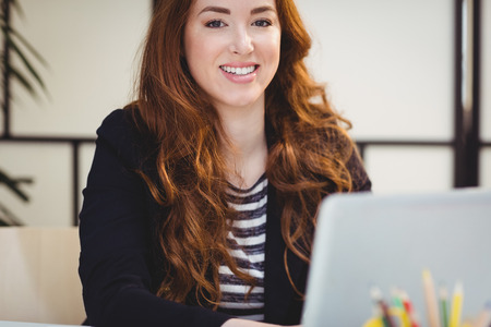 Portrait of confident beautiful young executive using laptop at office