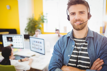 Portrait of happy young male executive wearing headphones at creative office