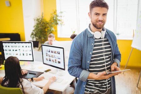 Portrait of happy young male executive using digital tablet at creative office
