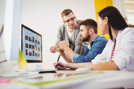 Male executive assisting young colleagues at creative officeの写真素材