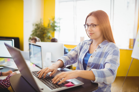 Smiling female graphic designer working with laptop in creative office